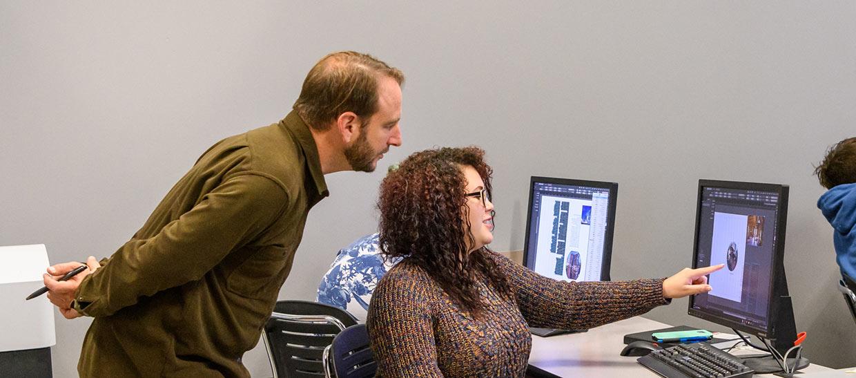 Digital media student and instructor working on a computer